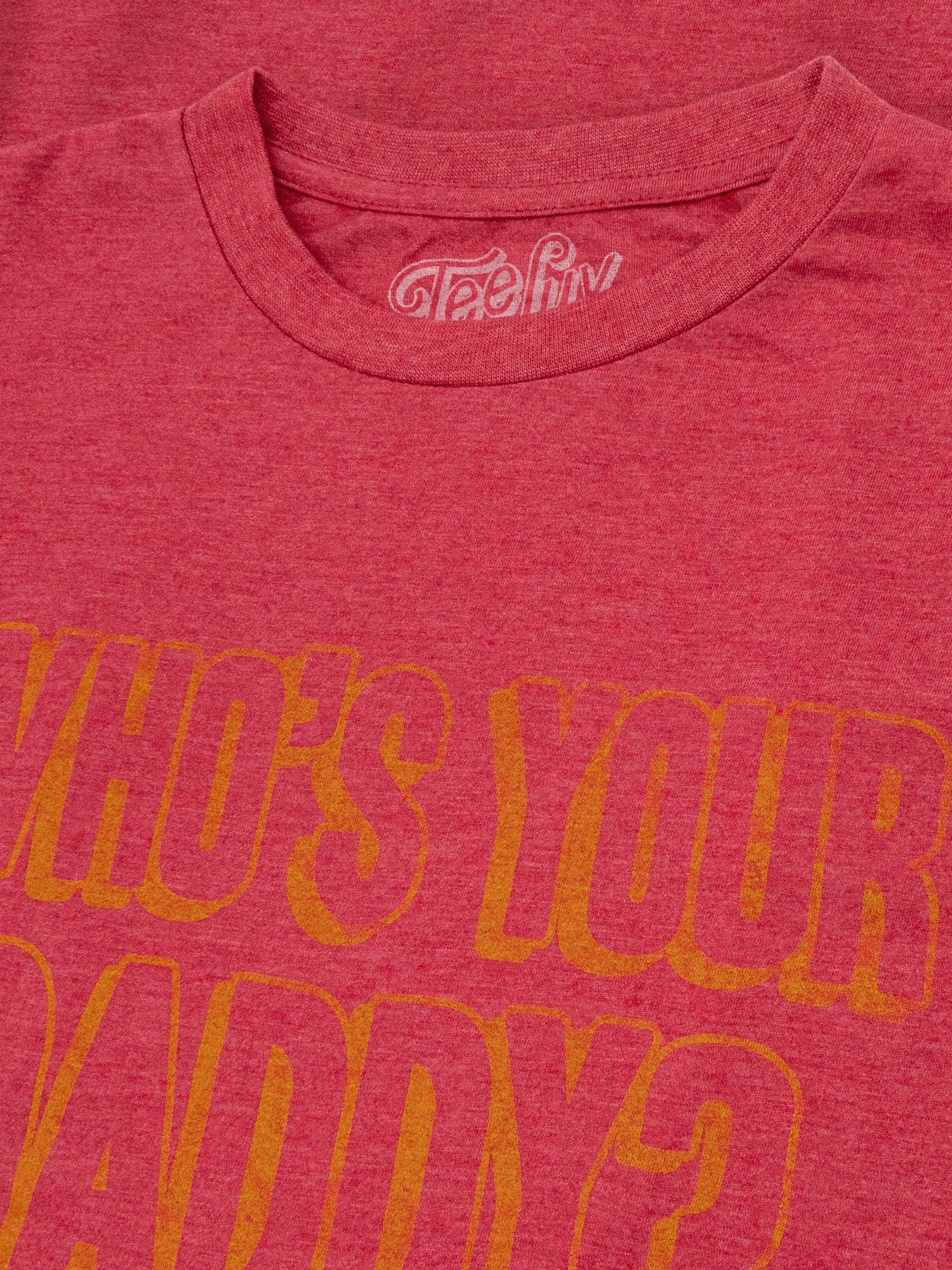 Red t-shirt with yellow text 'WHO'S YOUR DADDY?' and a visible brand logo on a red background.