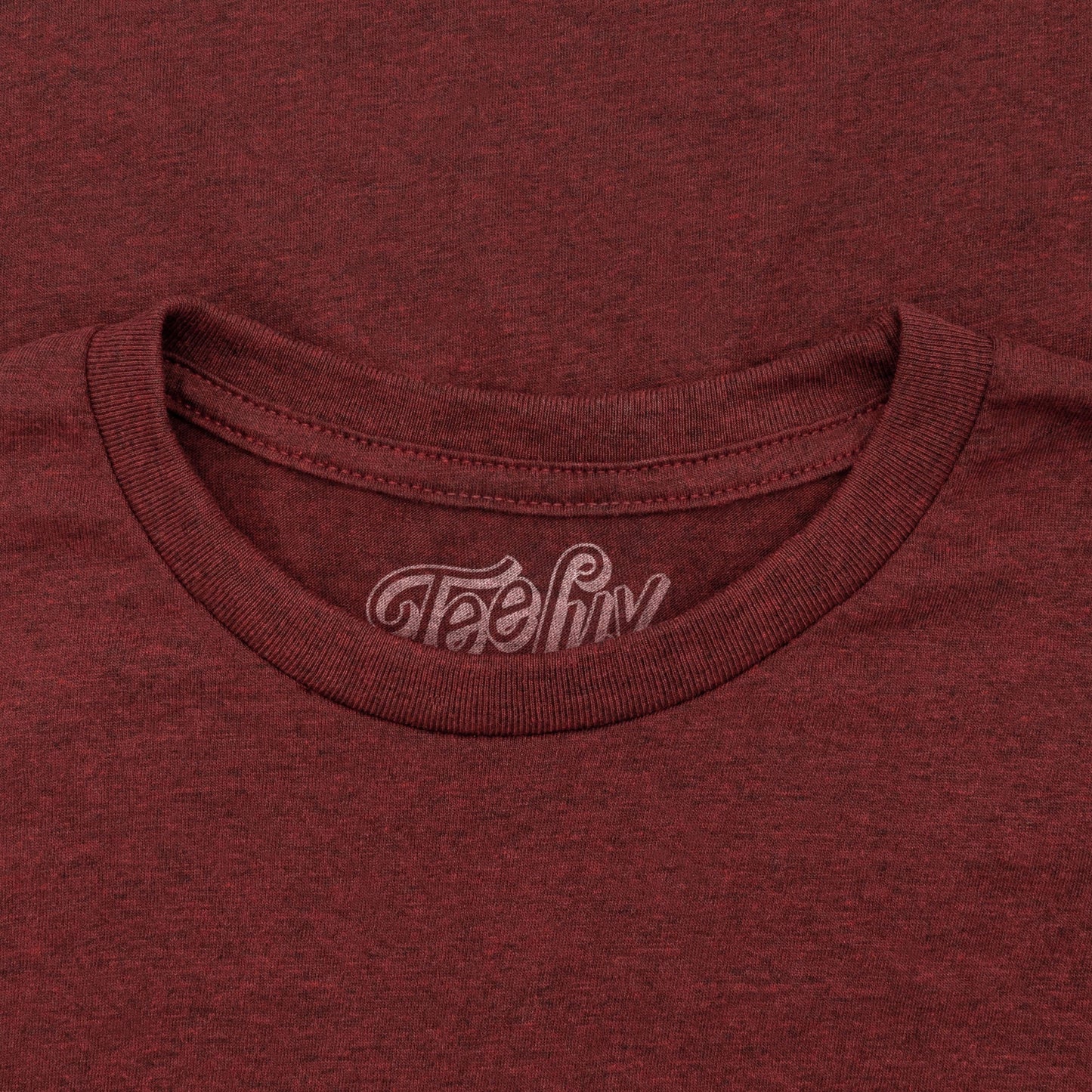 Close-up of a maroon t-shirt with 'Teefly' logo on the collar.