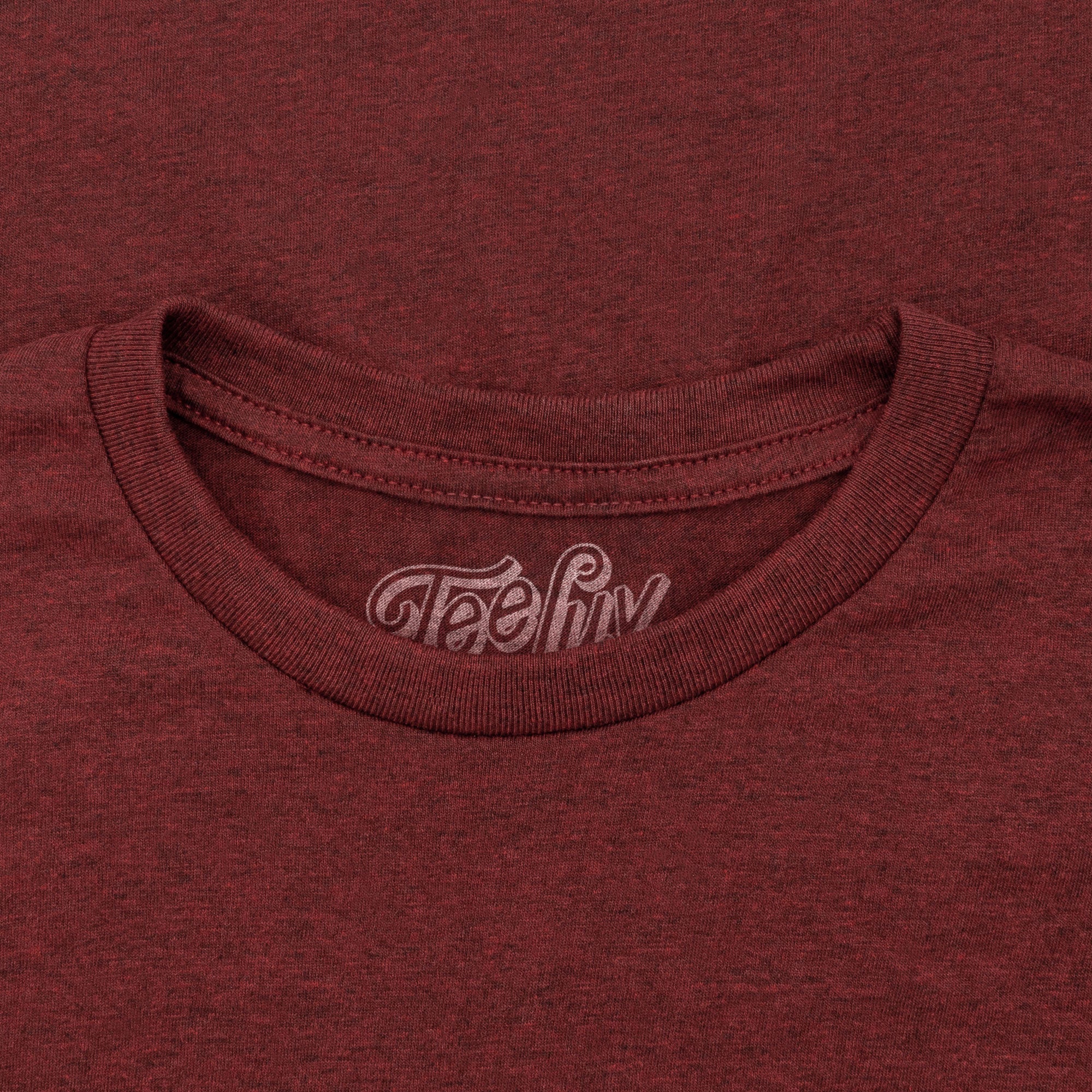 Close-up of a maroon t-shirt with 'Teefly' logo on the collar.