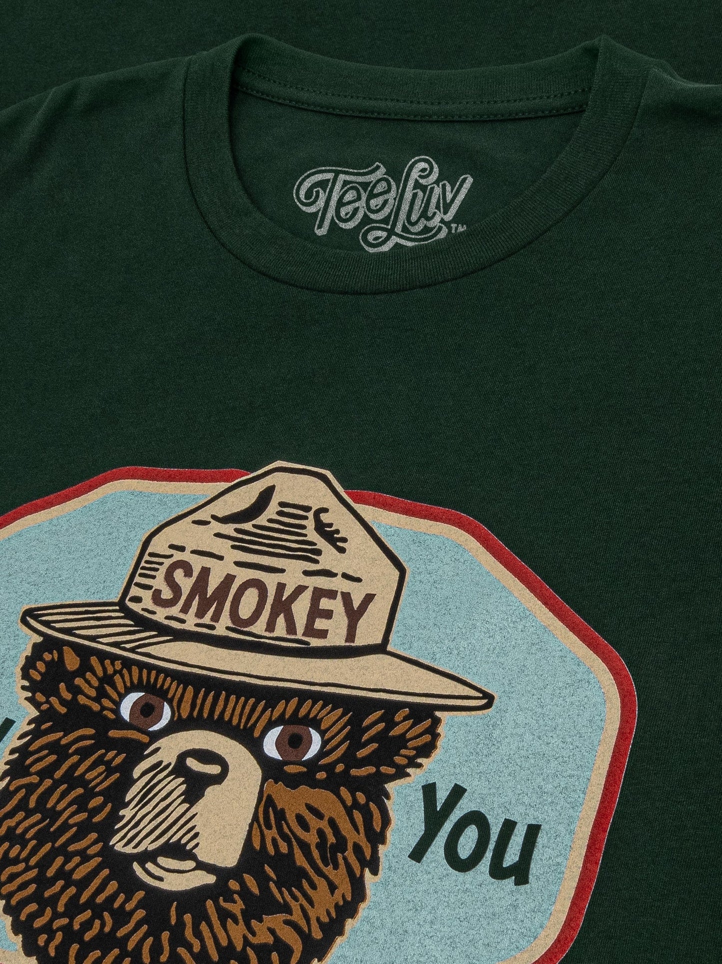 Dark green t-shirt with Smokey Bear graphic and 'Tee Luv' branding.
